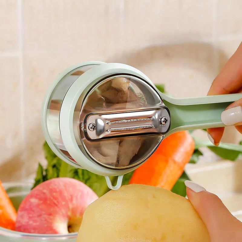 Hand using a potato peeler on a potato with fruits and vegetables in the background
