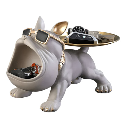 Decorative bulldog figurine with sunglasses and a tray on a reflective surface.