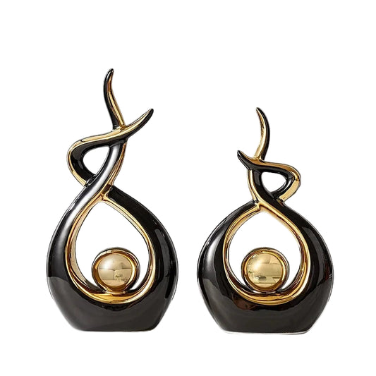 Two black and gold decorative items on a white surface with a gray background